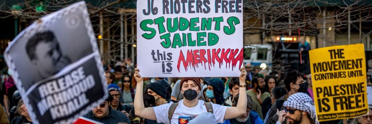 A protester holds a sign reading, "J6 rioters free, students jailed" 