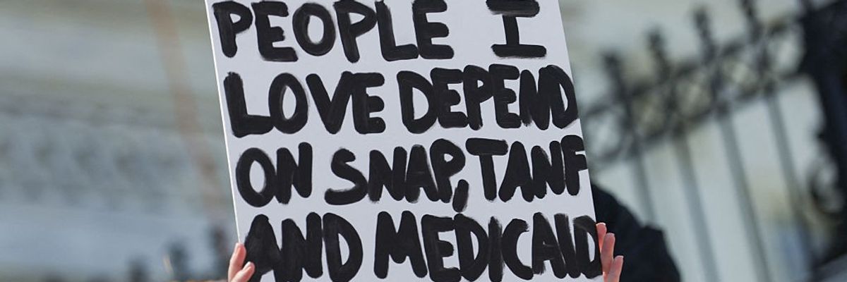 A sign reads, "People I love depend on SNAP, TANF, and Medicaid" 