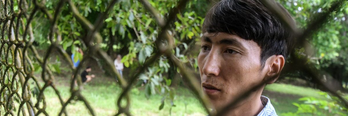​Afghan Mohammad Saber Asadi  talks to reporters through a fence