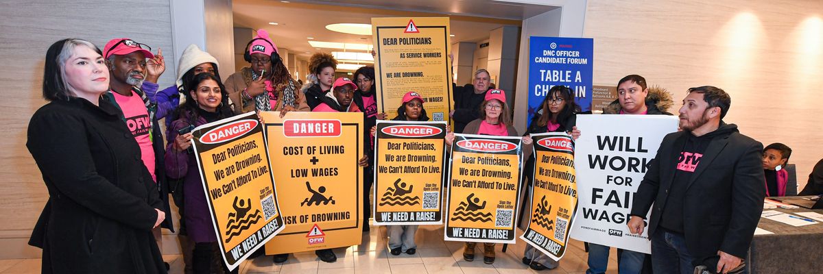 ​One Fair Wage supporters attend a rally and hold signs advocating for higher wages